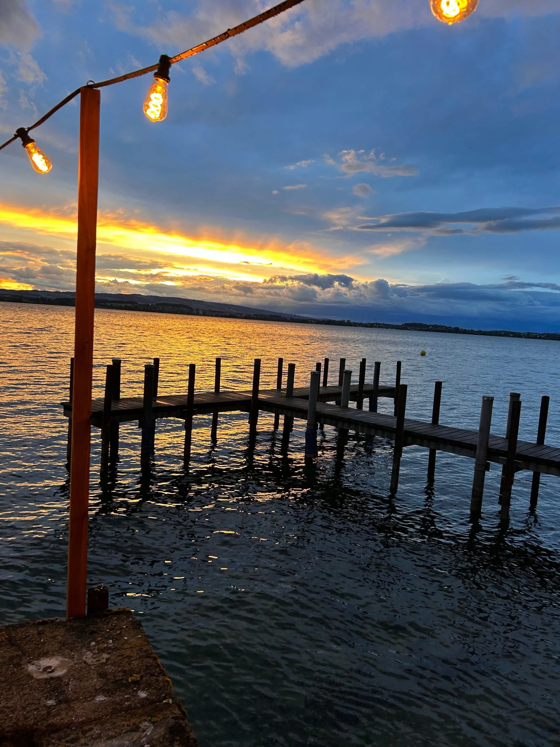 Sunset over Lake Zug with a jetty and string lights
